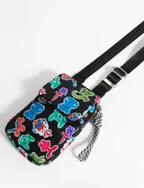 Porta celular negro con estampado de sirenas, langostas y peces en tonos rosa, rojo, verde y azul. Tiene correa larga regulable de tela negra y cierre con solapa y botón imantado.