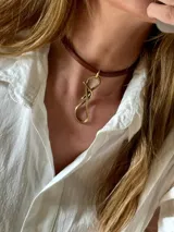 Gargantilla tipo choker de cuero marrón con dije central de bronce en forma de nudo infinito.