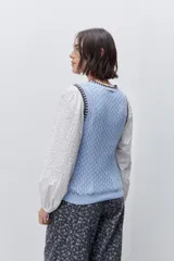 Chaleco de punto calado color celeste con cuello redondo y terminaciones en contraste marrón, de silueta cómoda y diseño sin mangas.
