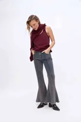 Jean de corte flare y tiro medio, color gris oscuro con efecto desteñido, costuras frontales marcadas y terminación desmechada en el bajo.
