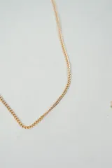 Set de tres collares dorados de diferentes largos y diseños: uno con bolitas espaciadas, otro liso y otro con dijes de flores.