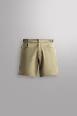 Pantalón corto de estilo técnico, confeccionado en tejido elástico color beige. Presenta cintura ajustable con cinturón de doble hebilla, cierre frontal con cremallera y botón a presión, bolsillos laterales y bolsillos con cierre oculto.