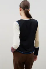 Remera de manga larga con diseño de bloques de color en tonos neutros, confeccionada con costuras externas visibles en color azul contrastante.