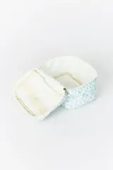 Necesser de viaje acolchado con estampado floral en tonos celestes y blancos. Posee cierre perimetral y asa superior para transporte.