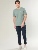 Remera blanca de algodón con cuello redondo y logo bordado de un pájaro en el pecho.