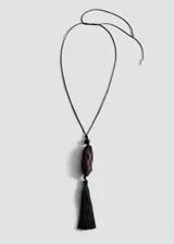 Collar largo ajustable con cordón negro, cuenta con un dije central de madera revestido en red negra y una borla colgante de flecos en la parte inferior.