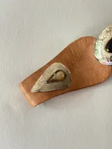 Cinto tipo faja de cuero color marrón, con diseño de piezas de cuero unidas y apliques metálicos plateados grabados con detalles geométricos y una piedra central oscura.