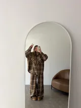 Pantalón de corte ancho y tiro alto con estampado de cuadros en tonos marrones y beige. Presenta cintura elástica y bolsillos laterales.