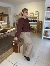 Blusa color chocolate con diseño de frunces elásticos en el frente y la espalda, mangas largas abullonadas con puños elásticos y corte peplum.