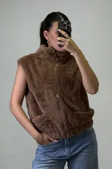 Chaleco de piel sintética color beige, con cuello alto, cierre frontal y bolsillos laterales.