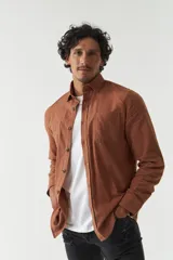 Camisa rústica de manga larga color marrón, con botones marrones, cuello clásico y dos bolsillos frontales con solapa.