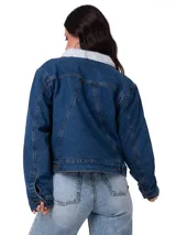 Chaqueta de jean azul con forro interior y cuello de sherpa blanco. Presenta cierre frontal con botones metálicos, bolsillos laterales y ajuste con botones en la cintura.