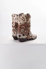 Bota de cuero color marrón con puntera fina y taco bajo. Presenta correas de cuero negro con apliques metálicos plateados.