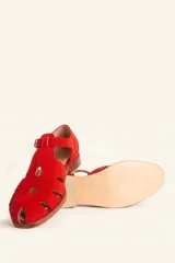 Sandalias de gamuza color marrón, estilo romano con diseño en T, tiras con aberturas laterales y cierre de hebilla metálica en el tobillo. Cuenta con tacón bajo de madera.