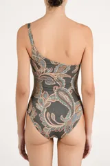 Traje de baño entero asimétrico con diseño de un solo hombro, decorado con cuentas de resina en el tirante. Presenta un estampado tipo paisley en tonos oscuros, ocres y azulados.
