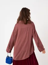 Camisa de raso color bordó con silueta suelta, manga larga, puños anchos y cierre frontal con botones a tono.