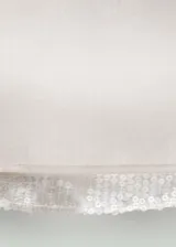 Falda corta de tiro medio con diseño recto y doble capa, confeccionada en tejido bordado con lentejuelas brillantes. Cuenta con cierre de cremallera lateral.