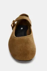Zapato plano tipo bailarina en serraje color marrón. Tiene escote redondo y cierre mediante hebilla en el empeine.