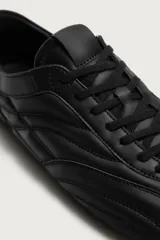 Zapatilla de cordones con diseño acolchado y paneles combinados. Presenta una silueta de perfil bajo con suela ultrafina a tono.