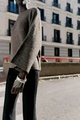 Jersey de punto color marrón oscuro con lentejuelas plateadas, cuello barco y manga larga acampanada.