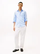 Camisa celeste de corte slim, confeccionada en tejido dobby de algodón con Flex Technology, cuello con botones, puños redondeados con dos botones y logo de Tommy Hilfiger bordado en el pecho.