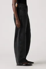 Pantalón de jean de corte baggy con diseño barrel, de tiro medio y color negro lavado. Presenta costuras laterales curvas que acentúan su silueta amplia y estructurada.