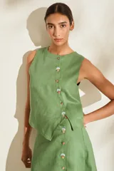 Top verde de lino, sin mangas, con cuello redondo y diseño de cartera asimétrica con botones. Presenta detalles bordados en los ojales.