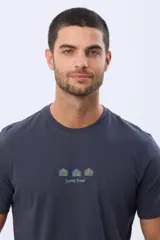 Remera de manga corta color azul oscuro, con cuello redondo y detalle de bordado pequeño en el centro del pecho que representa tres figuras geométricas con forma de árboles y el texto Legacy Brand.