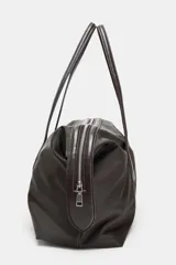 Bolso de hombro con diseño alargado confeccionado en nylon de color marrón oscuro. Presenta doble asa de mano en material a contraste, cierre superior con cremallera metálica y botones laterales decorativos.