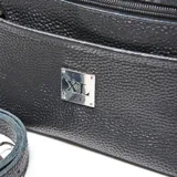 Bandolera de cuero con textura granulada, cuenta con doble asa de mano y correa larga ajustable y extraíble. Presenta un bolsillo frontal con cierre y placa metálica con logo de la marca en el centro.