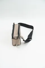 Bandolera de diseño rectangular en color negro, confeccionada en material texturizado. Cuenta con una correa de hombro ajustable y extraíble, cierre superior y tiradores laterales decorativos.