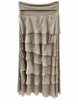 Pollera larga beige con múltiples volados horizontales y detalles de flecos en los bordes.
