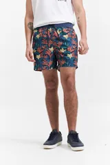 Short de baño con estampado de hojas y flores en tonos verde, naranja y amarillo sobre fondo azul. Tiene cintura elástica con cordón ajustable, dos bolsillos laterales y uno trasero.