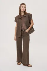 Pantalón jean de tiro medio, color negro, de corte amplio y silueta extra wide leg. Presenta diseño clásico de cinco bolsillos, cierre frontal con botón y cremallera, y detalle de tachas metálicas aplicadas a lo largo de los laterales.