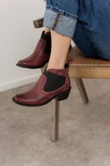 Botín negro de cuero con elásticos laterales, taco bajo y tirador trasero.