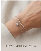 Pulsera doble de plata 925, compuesta por una cadena fina con un dije ovalado de circonia y otra cadena con un dije de barra pavé con circonias brillantes.