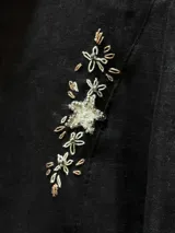 Camisa de lino color crudo con cuello clásico y cierre frontal de botones. Presenta delicados bordados artesanales florales distribuidos por toda la prenda.