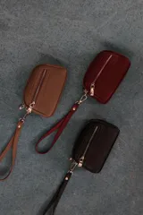 Monedero de dama con correa de mano, confeccionado en material símil cuero con textura granulada. Cuenta con doble compartimento principal con cierre y un bolsillo frontal con cierre, ideal para organizar tarjetas, billetes y monedas.