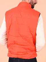 Chaleco negro acolchado con cierre frontal y ribete amarillo flúor en cuello, sisas y bolsillos.