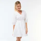 Vestido corto blanco con diseño de bordado inglés, escote en V con botones frontales, mangas abullonadas tres cuartos y detalle de lazo ajustable en la cintura con falda escalonada.