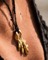 Collar con dije de bronce macizo con forma orgánica irregular, similar a un coral, suspendido de un cordón negro de seda natural anudado.