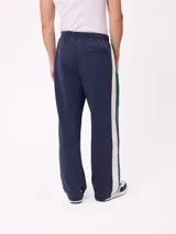 Pantalón tipo babucha de la marca Rusty, color azul petróleo con franjas laterales en color bordó. Presenta cintura elástica con cordón ajustable y logo bordado en la pierna izquierda.