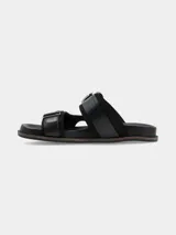 Sandalia de cuero negro con diseño de doble tira ancha, hebillas metálicas grandes y detalles de apliques plateados estilo western.