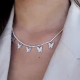 Collar plateado con cadena de eslabones pequeños y siete dijes de mariposas cubiertos de cristales.