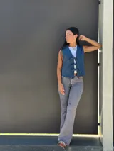 Chaleco de jean azul con cierre frontal mediante lazos ajustables, sin mangas y corte recto.