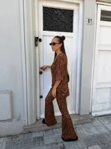 Conjunto de dos piezas compuesto por una remera de manga corta y un pantalón de corte acampanado, ambos confeccionados en lanilla con estampado animal print en tonos marrones.