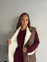 Chaleco largo de eco cuero color marrón con interior y detalles de corderito en solapas y bolsillos frontales.