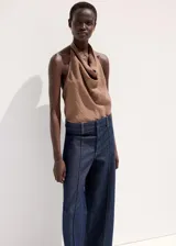 Pantalón de jean azul oscuro con corte recto y tiro medio. Presenta costuras verticales marcadas en el frente de cada pierna y diseño de pierna ancha.