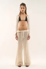 Pantalón tejido de punto color crema, de corte recto y holgado, con cintura elástica ajustable mediante cordón.