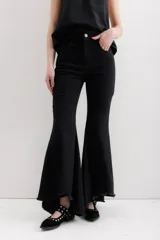 Pantalón de jean elastizado color negro, con volados en la parte baja de la pierna y ruedo descosido con juego de largos (más largo en la espalda que en la delantera).